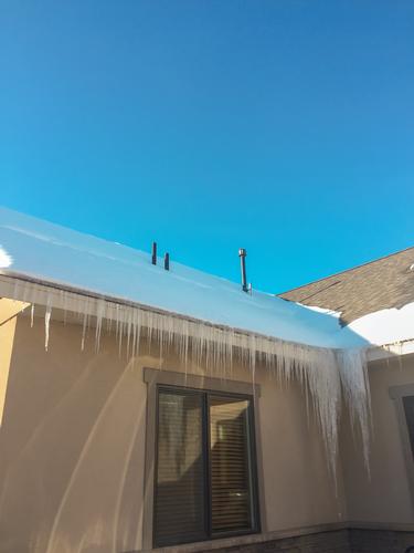 Icicles hang down from the valley of a roof. 